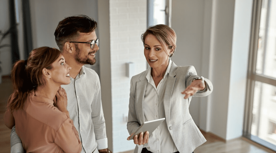 Happy real estate agent talking to a couple while showing them a new apartment